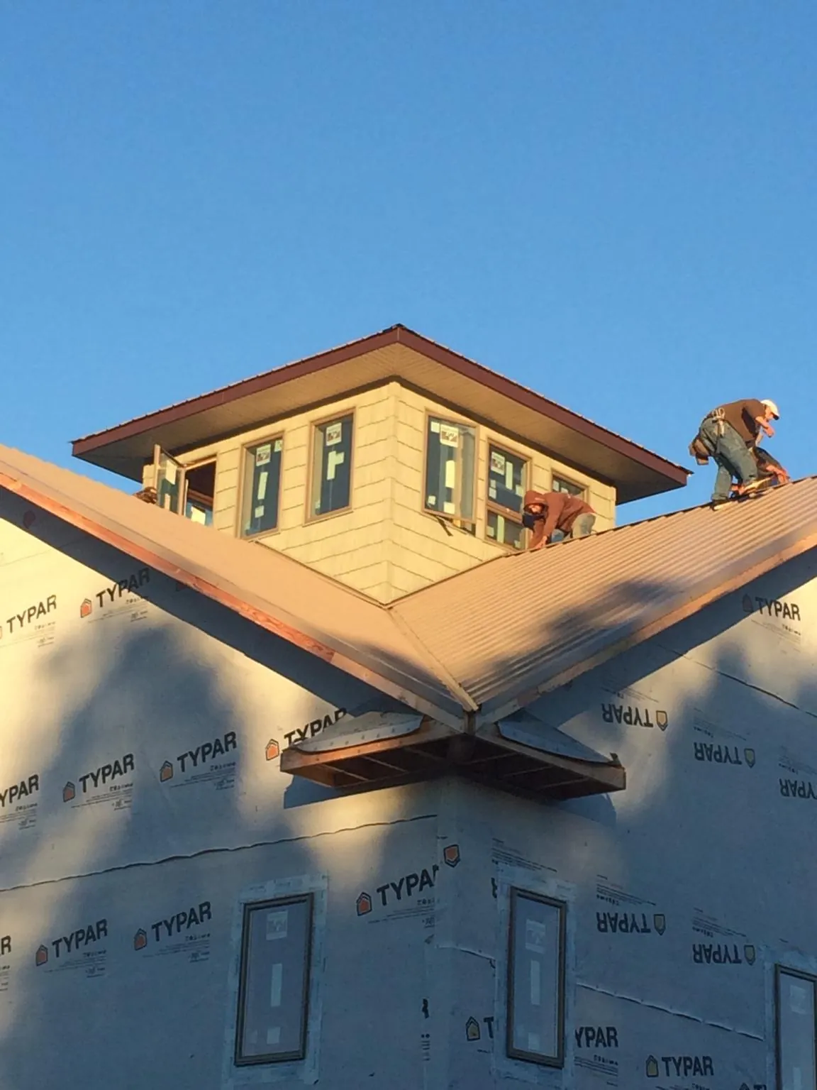 Roofers working around a rooftop cupola on a new metal roof at sunset — Roof Waterproofing in Saint Charles by Roofing Brothers